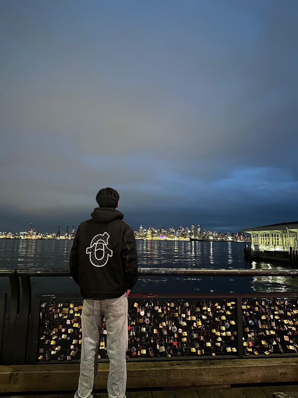 Alberto Aguirre de espaldas, mirando el skyline de Vancouver de noche desde el muelle